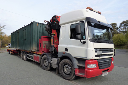 green shipping container loaded on hiab lorry