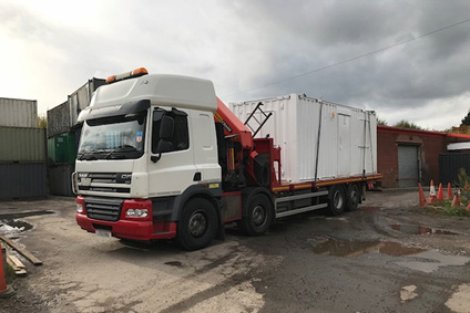 side picture of white shipping container on the hiab lorry